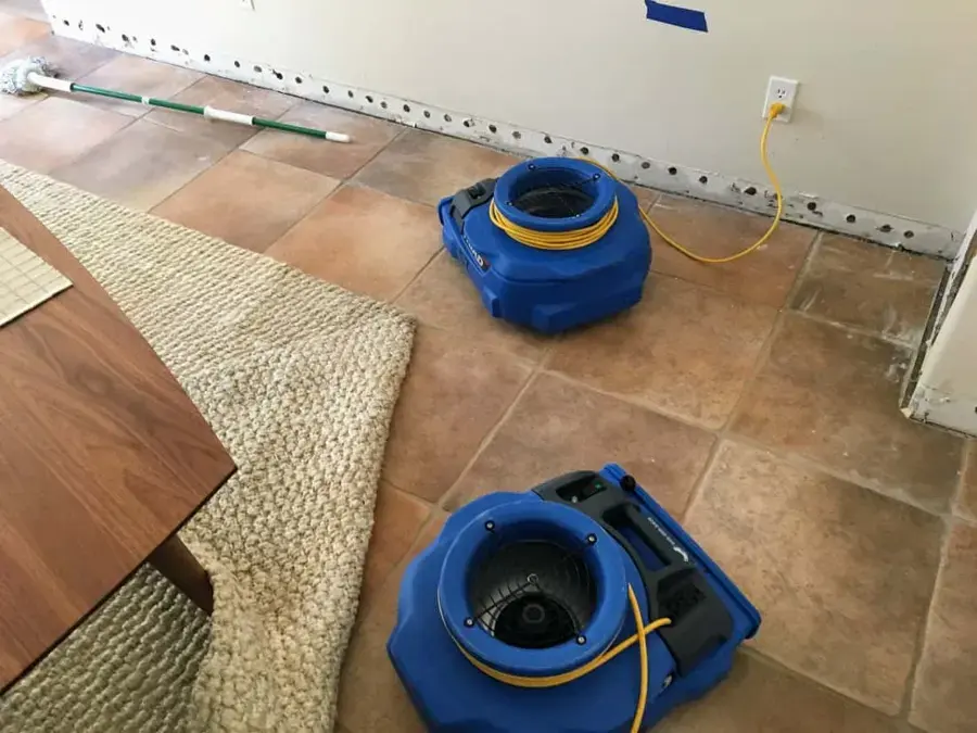 Air movers drying a tile floor after the lower drywall was cut back in a La Puente home