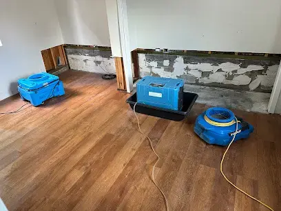 Drywall cut above the wet line with a dehumidifier and air mover drying the room