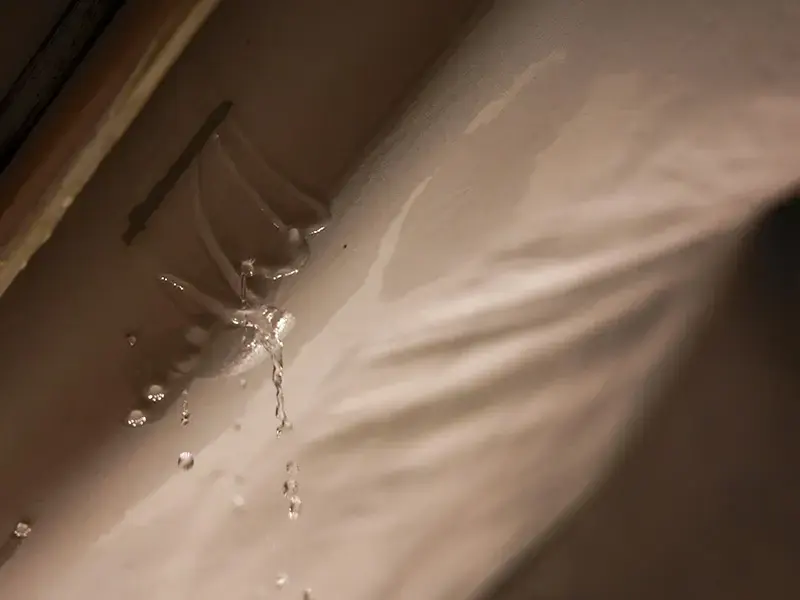 Water dripping through a stained ceiling from a leak above