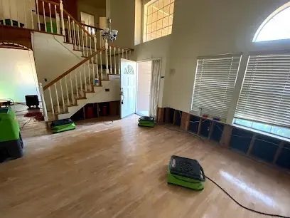 Air movers drying a living room after the lower drywall was cut away