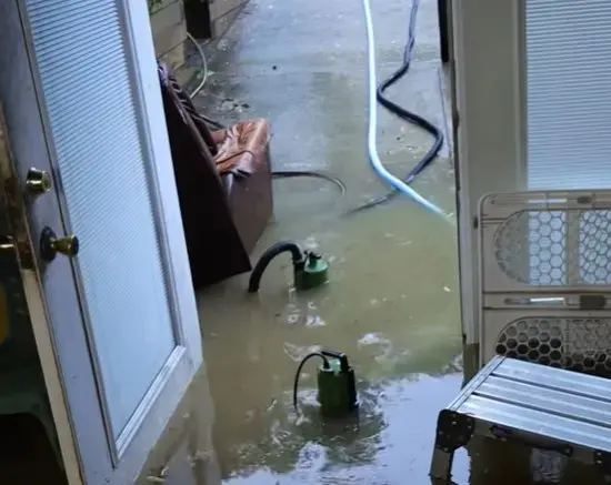 Pump pulling standing water out of a flooded room in a La Puente home