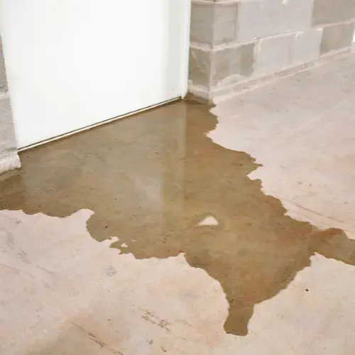 Water pooled across a concrete floor beside a wall after a tank leak